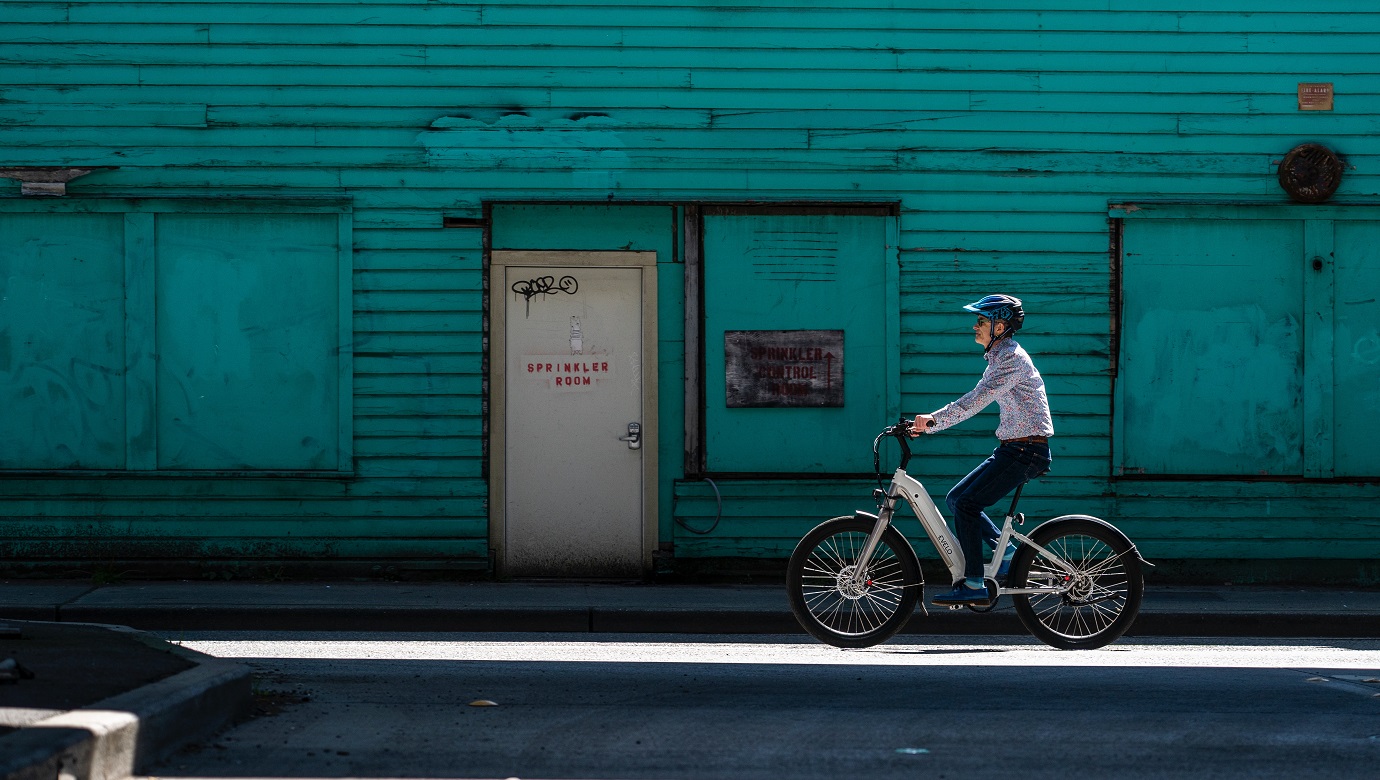Starszy mężczyzna jeździ po ulicy miasta rowerem elektrycznym